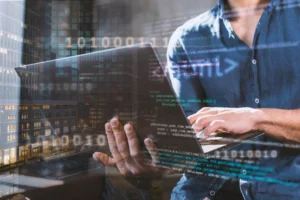 Pessoa usando um laptop com código digital e gráficos sobre computação em borda (Edge Computing), simbolizando tecnologia avançada e processamento de dados próximo ao usuário.