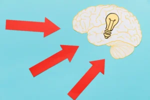 Imagem ilustrativa demonstrando o efeito ancoragem e a aversão à perda na estratégia de preço, com setas indicando influência no pensamento, representado por um cérebro com uma lâmpada.