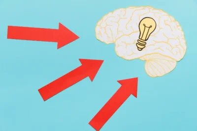 Imagem ilustrativa demonstrando o efeito ancoragem e a aversão à perda na estratégia de preço, com setas indicando influência no pensamento, representado por um cérebro com uma lâmpada.